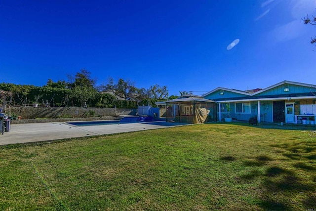 rear view of property featuring a fenced in pool, a lawn, fence, a gazebo, and a patio area