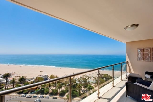 balcony with a water view and a view of the beach