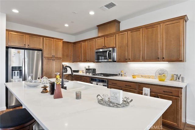 kitchen with a kitchen island with sink, appliances with stainless steel finishes, sink, and a kitchen bar