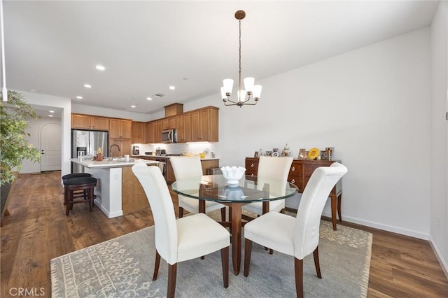 dining space featuring dark hardwood / wood-style floors, sink, and a chandelier