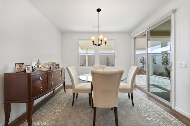 dining area featuring dark hardwood / wood-style flooring and an inviting chandelier