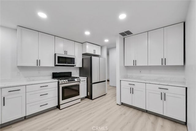 kitchen featuring light stone countertops, appliances with stainless steel finishes, light hardwood / wood-style flooring, and white cabinetry