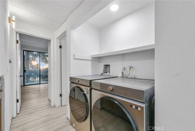 laundry area with washing machine and dryer and light wood-type flooring