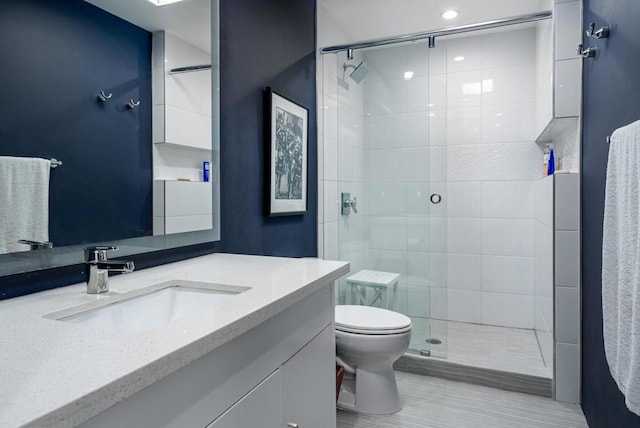 bathroom featuring a shower with door, vanity, and toilet