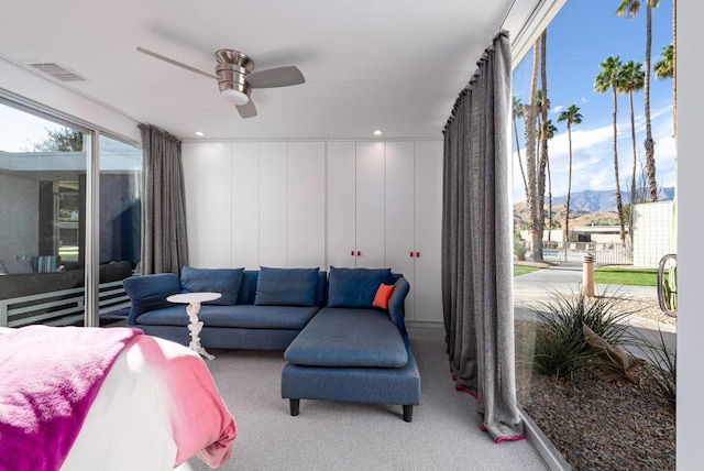 bedroom with light carpet, ceiling fan, and a mountain view