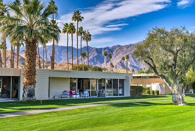 rear view of property with a mountain view and a lawn