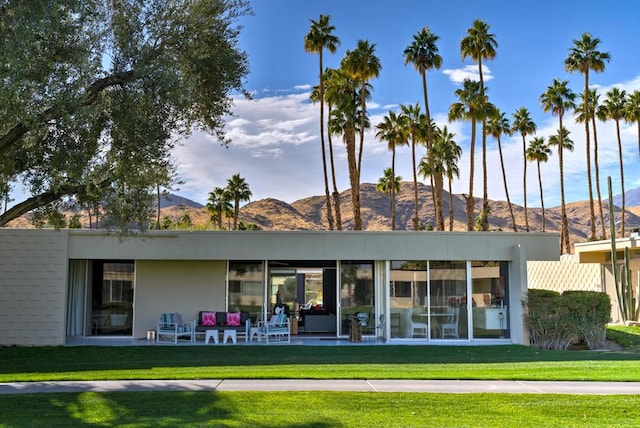 back of property with a lawn and a mountain view