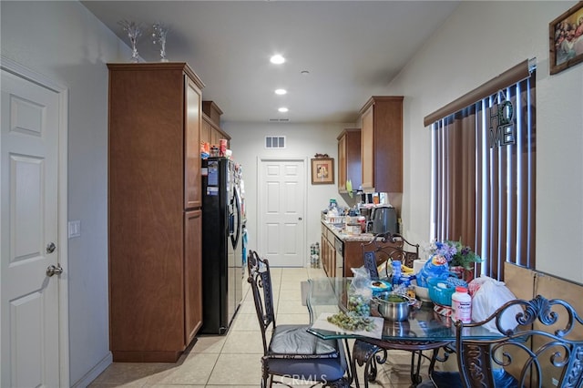 kitchen featuring black fridge, light tile patterned flooring, and light stone countertops