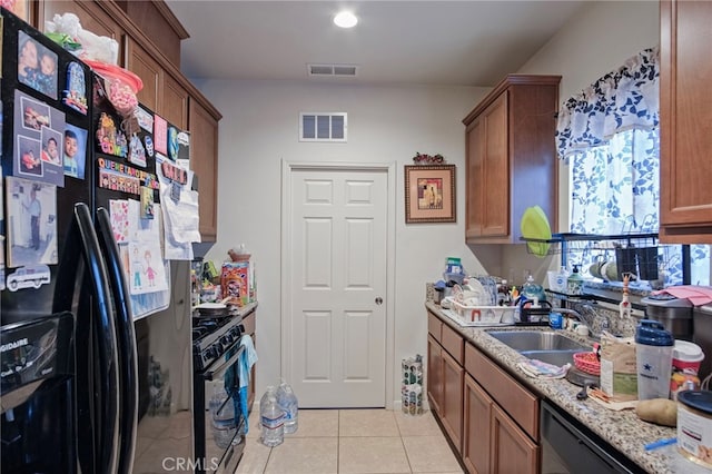 kitchen featuring light stone counters, light tile patterned floors, black appliances, and sink