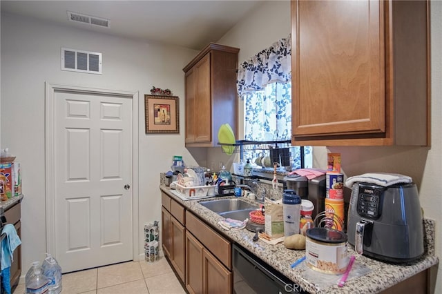 kitchen with sink, dishwasher, light stone counters, and light tile patterned floors