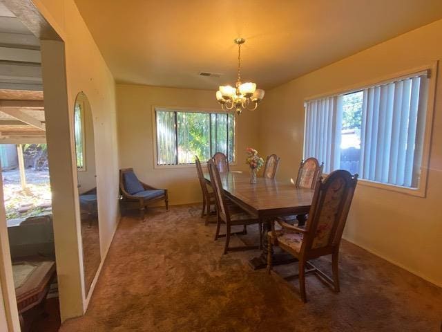 carpeted dining space with a chandelier