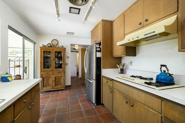 kitchen featuring white gas stovetop, stainless steel fridge, track lighting, and dark tile patterned flooring