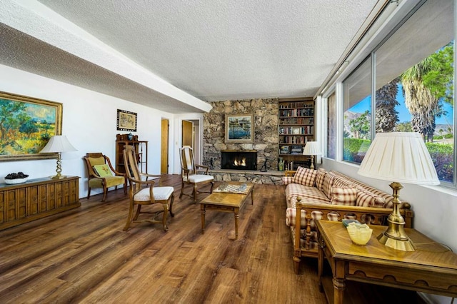 sitting room featuring hardwood / wood-style floors, a textured ceiling, built in features, and a stone fireplace