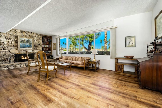 living room with a textured ceiling, a fireplace, and hardwood / wood-style flooring