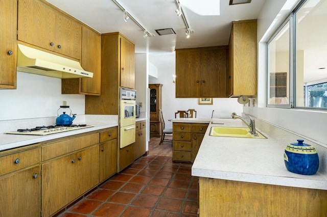 kitchen with white appliances, dark tile patterned flooring, and sink