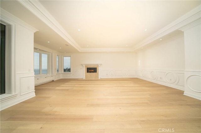 unfurnished living room featuring light hardwood / wood-style floors, crown molding, and a tray ceiling