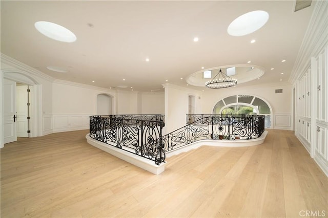 hall with light wood-type flooring and crown molding