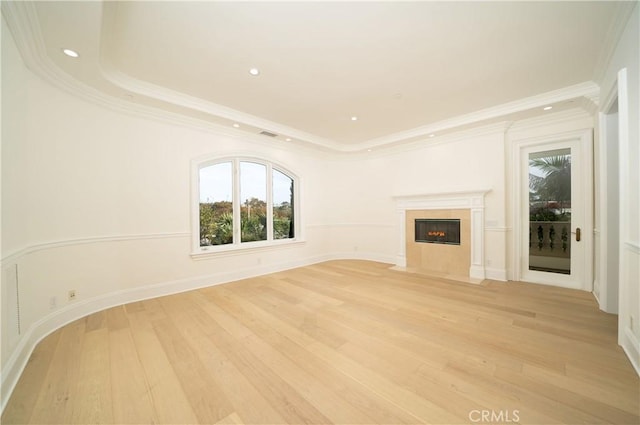 unfurnished living room featuring a raised ceiling, light hardwood / wood-style flooring, and ornamental molding