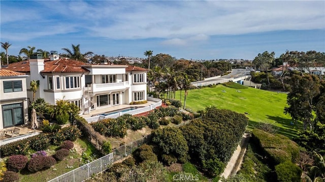 rear view of house with a patio, a balcony, a fenced in pool, and a yard