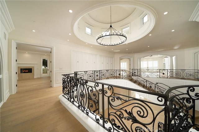 hallway with crown molding, a chandelier, and light hardwood / wood-style floors