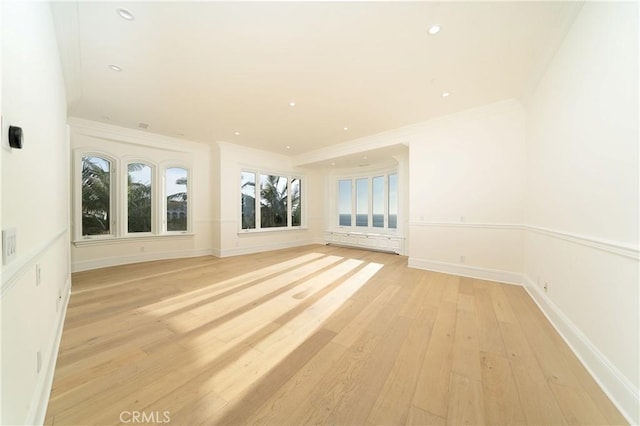 spare room featuring light wood-type flooring and ornamental molding