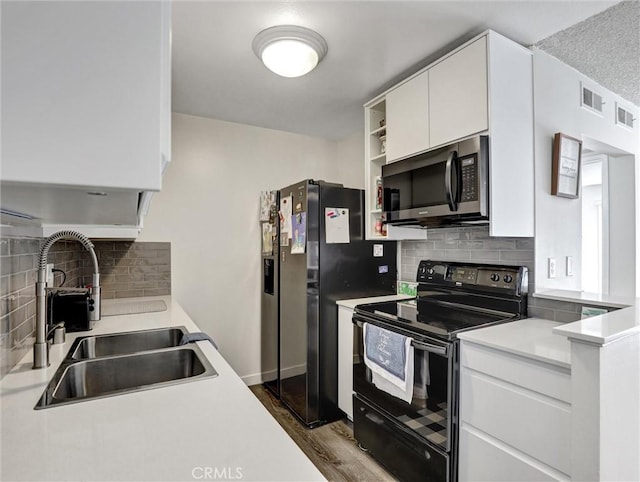 kitchen featuring dark wood-style flooring, light countertops, white cabinetry, a sink, and black appliances