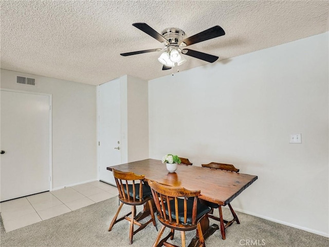 dining space featuring light tile patterned floors, light colored carpet, visible vents, ceiling fan, and a textured ceiling