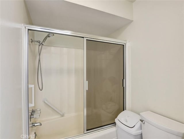 bathroom featuring enclosed tub / shower combo and toilet