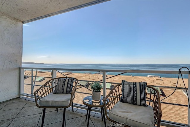 balcony with a water view and a view of the beach