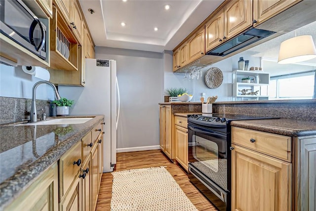 kitchen featuring sink, black range with electric stovetop, dark stone countertops, a raised ceiling, and light hardwood / wood-style flooring