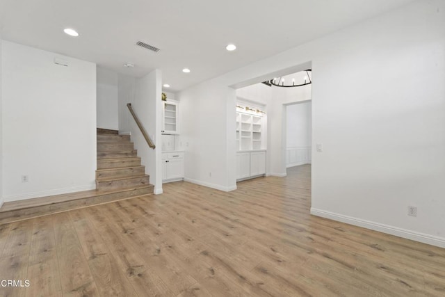 unfurnished room featuring an inviting chandelier and light hardwood / wood-style floors