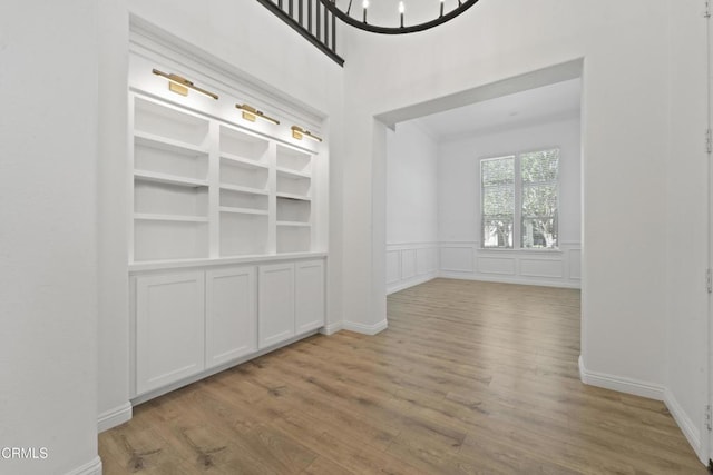 interior space with light hardwood / wood-style floors, built in shelves, and a chandelier