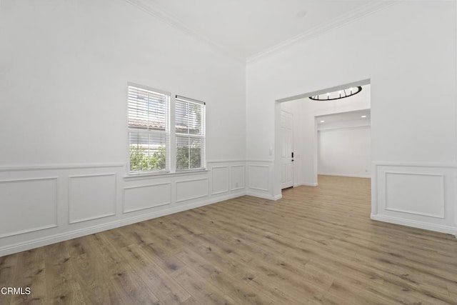 spare room featuring light wood-type flooring and crown molding