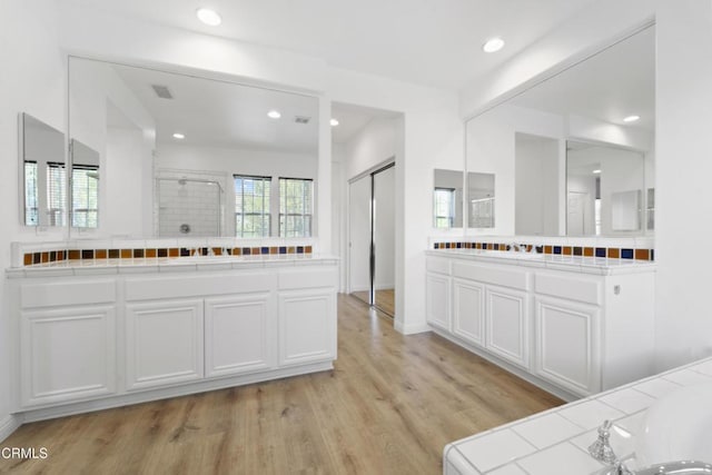 bathroom with a shower, hardwood / wood-style floors, and vanity