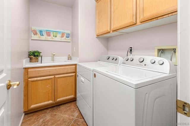 laundry area featuring sink, washing machine and dryer, light tile patterned floors, and cabinets