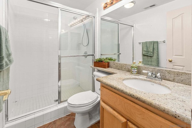 bathroom featuring vanity, toilet, tile patterned floors, and a shower with shower door