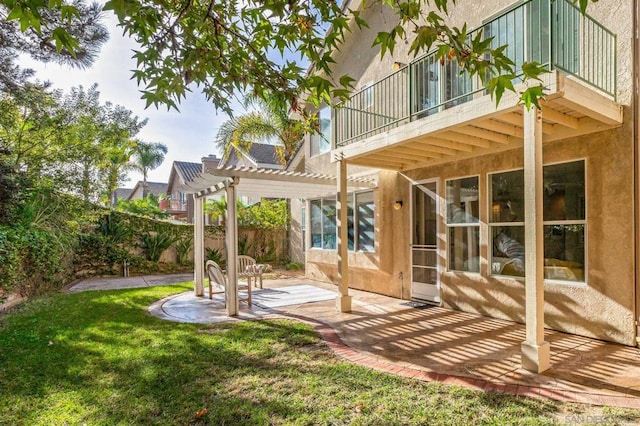 rear view of house with a balcony, a patio area, a yard, and a pergola