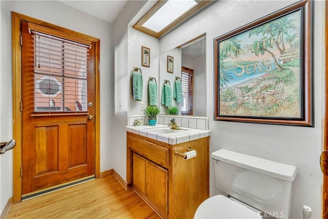 bathroom with toilet, hardwood / wood-style floors, and vanity