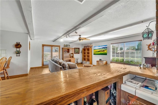 dining space with ceiling fan, plenty of natural light, beamed ceiling, and light hardwood / wood-style floors