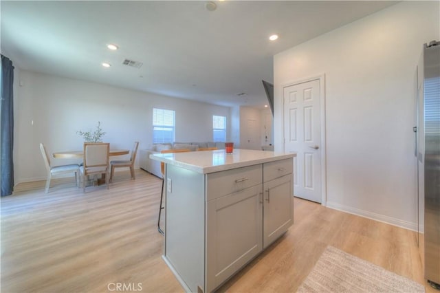 kitchen with gray cabinetry, light hardwood / wood-style flooring, and a center island