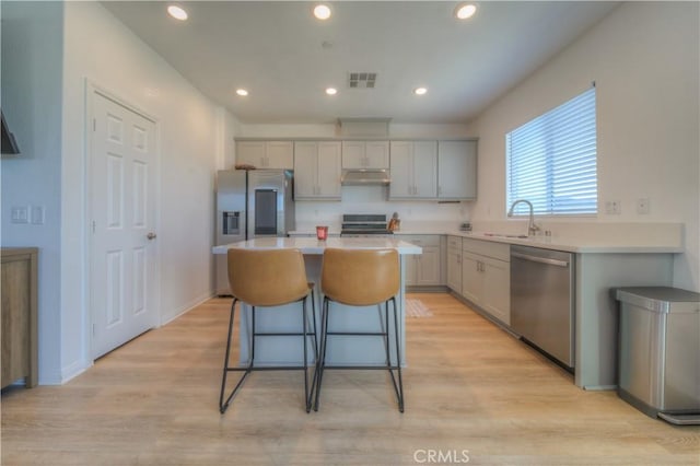 kitchen with light wood-type flooring, appliances with stainless steel finishes, gray cabinets, and a center island