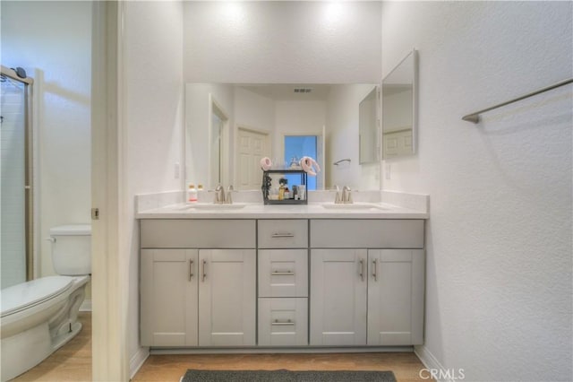 bathroom with toilet, an enclosed shower, vanity, and hardwood / wood-style floors