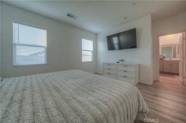 bedroom featuring ensuite bath and light wood-type flooring