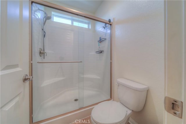 bathroom featuring a shower with shower door and toilet