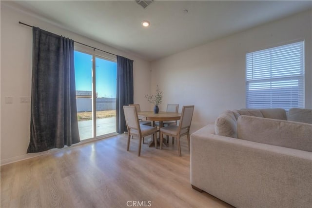 dining area with light hardwood / wood-style floors and a water view