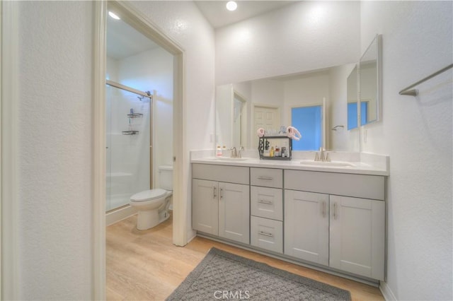 bathroom featuring toilet, vanity, hardwood / wood-style floors, and a shower with shower door