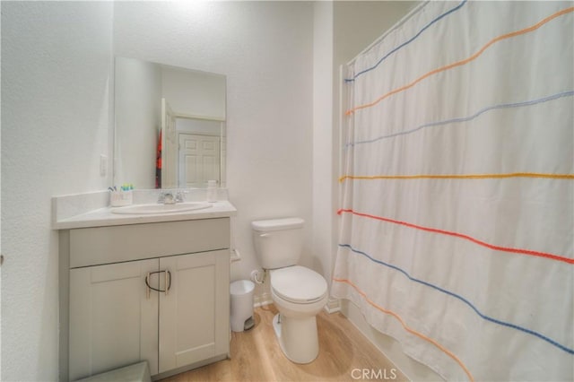 bathroom featuring walk in shower, toilet, vanity, and hardwood / wood-style flooring