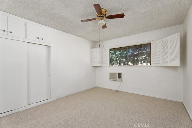 unfurnished bedroom featuring ceiling fan, a closet, light carpet, and a wall unit AC