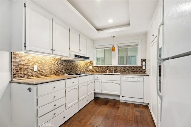 kitchen with white appliances, a raised ceiling, dark hardwood / wood-style flooring, white cabinets, and tasteful backsplash