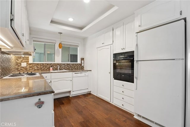 kitchen featuring white appliances, pendant lighting, a raised ceiling, tasteful backsplash, and white cabinetry